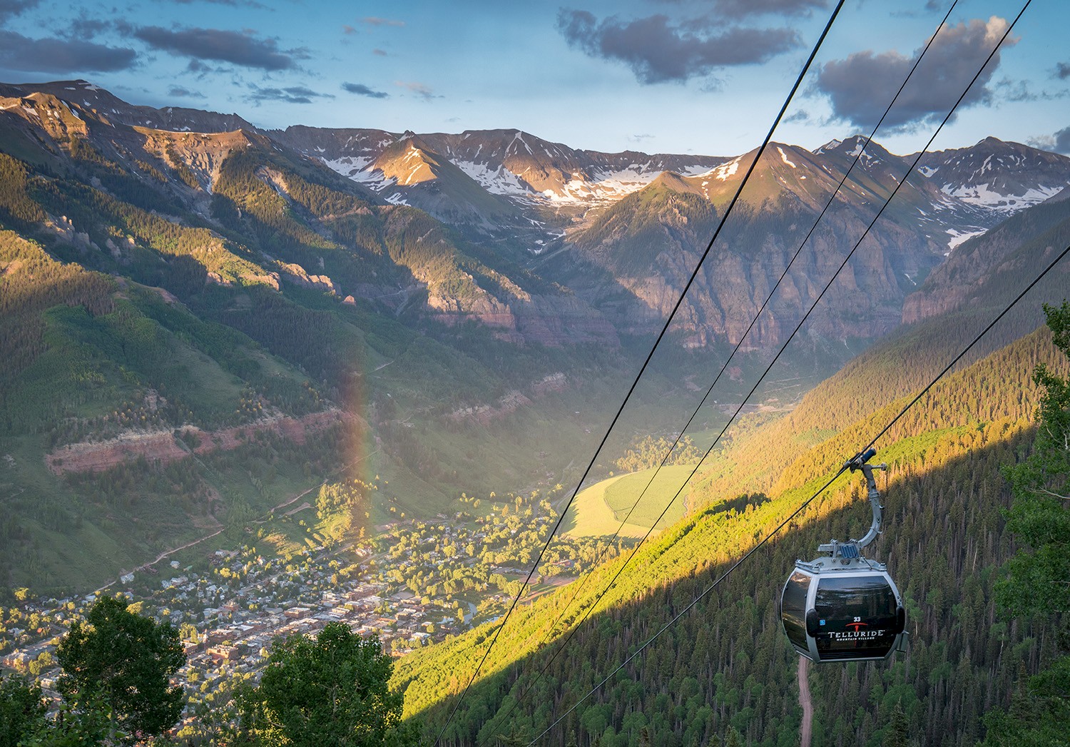 The gondola rises above Telluride Colorado with a rainbow in the sky